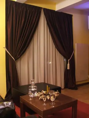 a table with wine glasses on it in front of a curtain at Vila Lira in Vrnjačka Banja