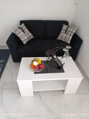 a living room with a black couch and a white coffee table at Garfield Family Apartman 2 in Soko Banja