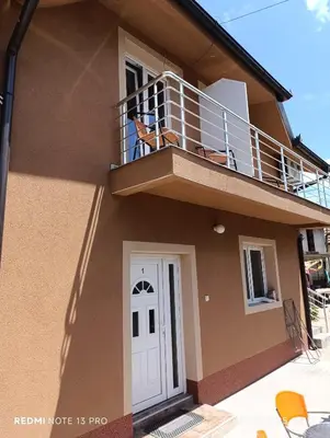 a house with two dogs sitting on a balcony at Garfield Family Apartman 2 in Soko Banja