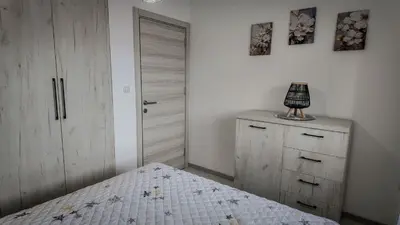a bedroom with a bed and a dresser with a lamp on it at Apartman Jovanović in Pirot