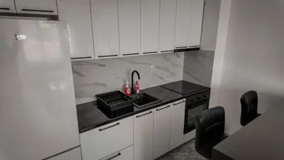 a white kitchen with a sink and a stove at Apartman Jovanović in Pirot