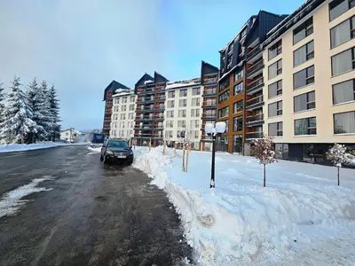 a car parked on a snow covered street next to buildings at Residence Hill Lux in Kopaonik