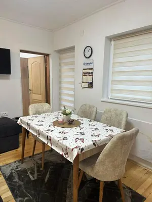a dining room with a table with chairs and a clock at Lily Apartmani Brzece in Brzeće