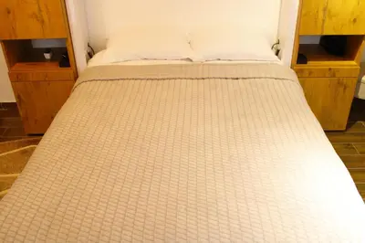 a bed in a room with a white bedspread at studio apartman Najdanović CENTAR in Vrnjačka Banja