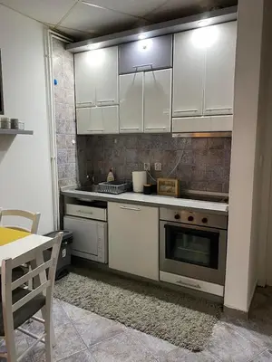 a kitchen with white cabinets and a stove top oven at Vila Plan Apartman 101 in Kopaonik