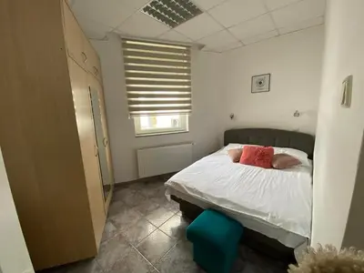 a bedroom with a bed with white sheets and red pillows at Vila Plan Apartman 101 in Kopaonik