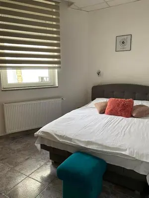 a bedroom with a bed with red pillows and a blue stool at Vila Plan Apartman 101 in Kopaonik
