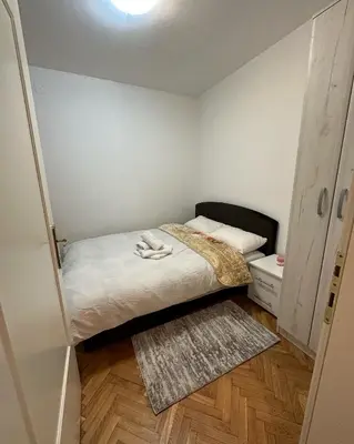 a small bedroom with a bed and a rug at Apartman Tiki R Vrnjacka Banja in Vrnjačka Banja