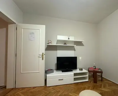 a living room with a television on a white cabinet at Apartman Tiki R Vrnjacka Banja in Vrnjačka Banja