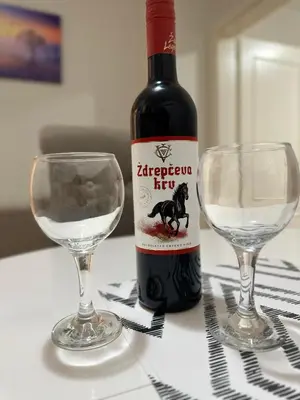 a bottle of wine next to two glasses on a table at Apartman Tiki R Vrnjacka Banja in Vrnjačka Banja
