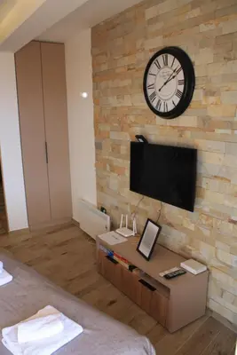 a hotel room with a clock on a brick wall at Silvani Kop NLux67, Milmari Apartments & Spa in Kopaonik