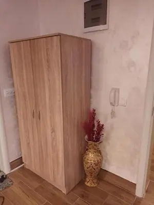 a wooden cabinet next to a vase in a room at Jelena Lux in Vrnjačka Banja