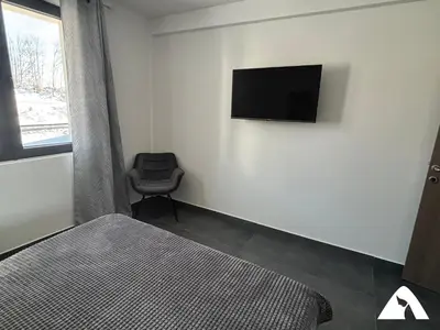 a bedroom with a bed and a television on the wall at Apartman ZAM in Kopaonik