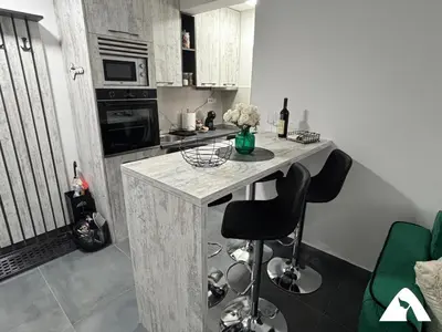 a kitchen with a counter and two stools in a room at Apartman ZAM in Kopaonik