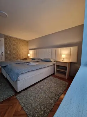 a bedroom with a bed and a table with two lamps at Apartman VRANJANKA in Vranje