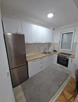 a kitchen with white cabinets and a stainless steel refrigerator at Apartman DRINA in Vranje