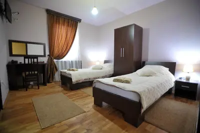 a bedroom with two beds and a table and a desk at Garni Hotel City in Kruševac