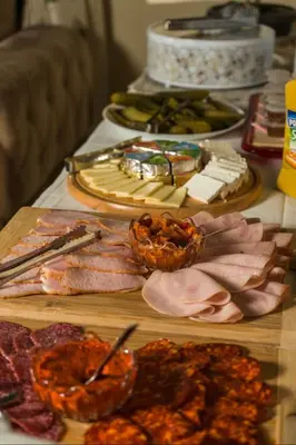 a table topped with different types of meats and food at Garni Hotel City in Kruševac