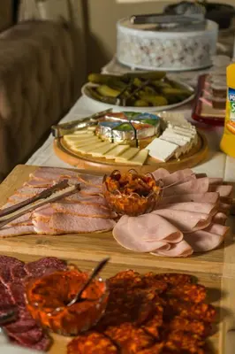 a table topped with different types of meats and food at Garni Hotel City in Kruševac
