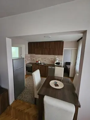 a kitchen with a wooden table and white chairs at Apartman Maks 1 in Pirot