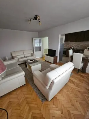 a living room with white couches and a television at Apartman Maks 1 in Pirot