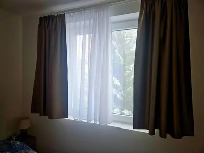 a window with blue and white curtains in a bedroom at Pogled Contra in Kopaonik
