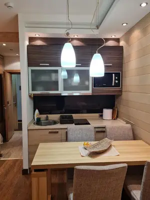 a kitchen with a wooden table and some lights at Apartmani Iva Kop Konaci Koznik402 in Kopaonik
