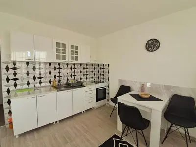 a kitchen with white cabinets and black and white tiles at La pera Kruševac in Kruševac