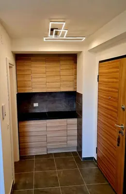 a walk in closet with wooden cabinets and a door at Beril lux apartman in Jagodina