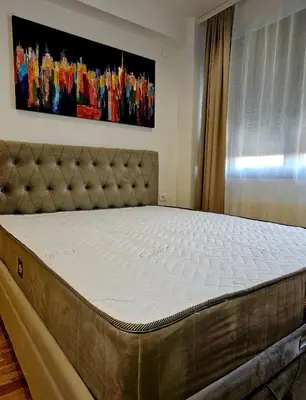 a bed in a bedroom with a mattressvisorvisorvisorvisor at Beril lux apartman in Jagodina