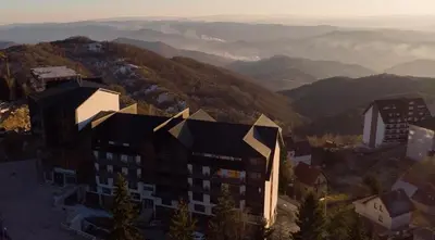 an aerial view of a building with mountains in the background at Residence Hill Kopaonik in Kopaonik