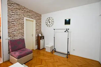 a living room with a chair and a brick wall at Apartman Dunja in Kraljevo