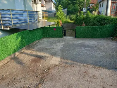 a driveway with a table and green hedge at Apartman Ilić in Vrnjačka Banja