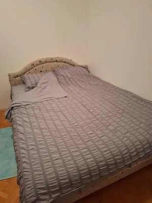 an unmade bed in a room with a white wall at Asami in Vrnjačka Banja
