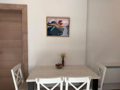 a dining room table with white chairs and a picture on the wall at Vila Elena in Kopaonik