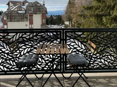 a bench on a balcony with a view of a building at Vila Elena in Kopaonik