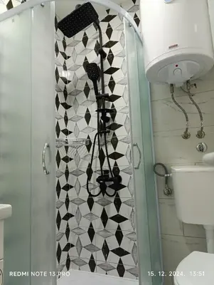 a bathroom with a shower with a black and white tiles at Garfield Family Studio 1 in Soko Banja