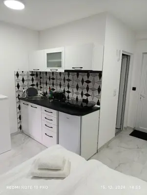 a white kitchen with a sink and a microwave at Garfield Family Studio 1 in Soko Banja