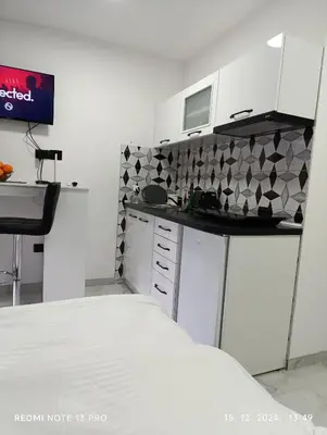 a kitchen with white cabinets and a black counter top at Garfield Family Studio 1 in Soko Banja