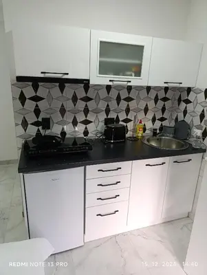 a white kitchen with a sink and a microwave at Garfield Family Studio 2 in Soko Banja