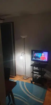 a living room with a flat screen tv and a lamp at Smart 2 in Niš
