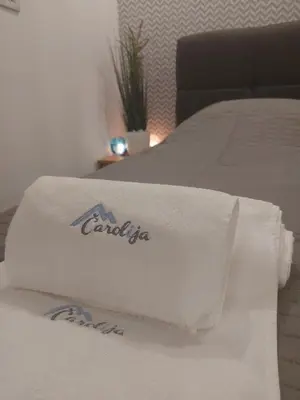 a white blanket on a bed with a canada towel at Apartman Čarolija, Sunčana planina in Kopaonik