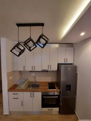 a kitchen with white cabinets and a stainless steel refrigerator at Apartman Čarolija, Sunčana planina in Kopaonik