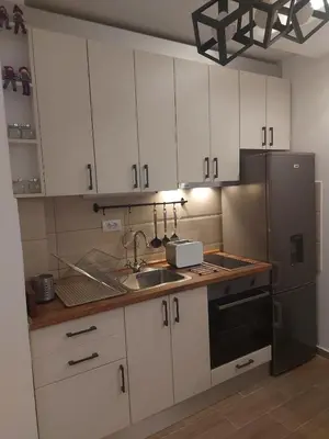 a kitchen with white cabinets and a sink and a refrigerator at Apartman Čarolija, Sunčana planina in Kopaonik