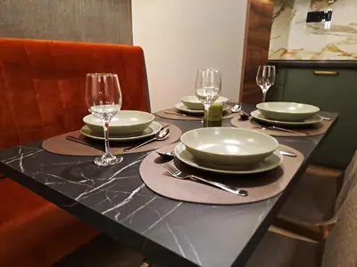 a table with plates and wine glasses on it at HILL Lux Apartman 1, FREE Secure private yard PARKING 2 place, DESIGNER home & WI-FI rooms & SMART TVx3 & 2 Bedroom & Rooms & Apartments Nis in Niš