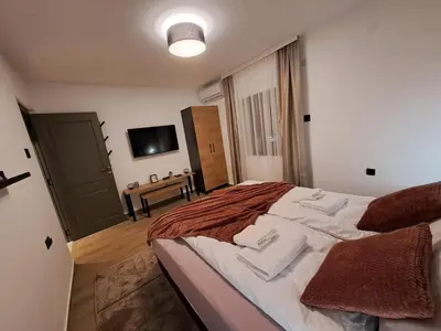 a bedroom with a large bed and a television at HILL Lux Apartman 1, FREE Secure private yard PARKING 2 place, DESIGNER home & WI-FI rooms & SMART TVx3 & 2 Bedroom & Rooms & Apartments Nis in Niš