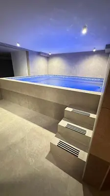 a swimming pool in a building with a blue pool at NORD VISTA Premium Alpine and SPA Experience in Kopaonik