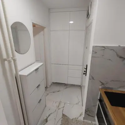 a bathroom with white cabinets and a marble floor at Apartman Sale lux in Leskovac