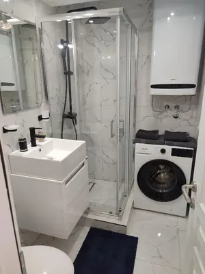 a bathroom with a shower and a washing machine at Apartman Sale lux in Leskovac
