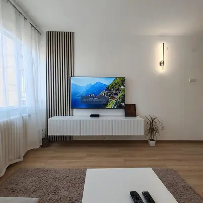 a living room with a flat screen tv on a white wall at Apartman Sale lux in Leskovac